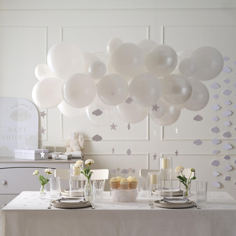 White balloons and decor in a room with a table set for a Baby Shower.