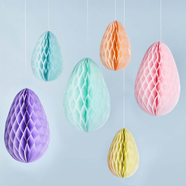 Hanging pastel-colored honeycomb Easter eggs on a light blue background